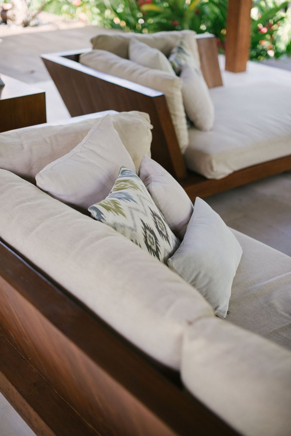 Outdoor lounge seating with cream cushions and dark wooden frames on a villa terrace